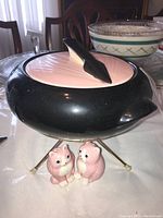 Side view of black and pink fondue pot sitting on metal stand along with pink cat salt and pepper shakers.