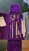 Photo showing the Hughes Owens geometry set with various drafting tools placed in purple velvet case.