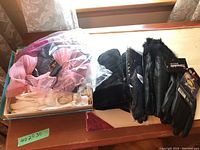 Several pairs of ladies gloves including formal cream gloves, pink decorative gloves in plastic bag, black leather gloves with fur trim, black quilted leather gloves, and Thinsulate gloves.