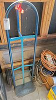 Full view of the metal hand cart showing blue tubular frame, rounded handle, and 'THREE FISHES' branding on horizontal bar.