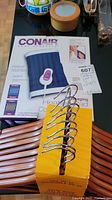 Photo of Conair heating massage pad box and set of 10 solid wood suit hangers with chrome hooks on a table.