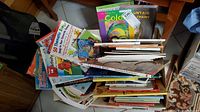 Top-down view of a stack of children's books showing colorful covers and titles, arranged loosely in a box.