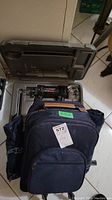 Open case showing Rotozip spiral saw tool and accessories inside alongside navy backpack on floor.