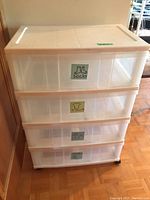Clear resin storage drawer unit with four drawers labeled for socks, t-shirts, pants and miscellaneous items, on wheels.