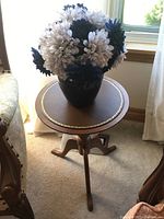 Side view of the pedestal table with vase and faux flowers, showing the gold inlay and the floral arrangement.