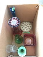 Overhead shot of all six vases and flower frog arranged in a cardboard box showing different shapes, colors, and sizes.