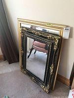 Two framed wall mirrors leaning against a wall, showing their overall size and style.