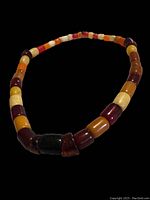 Full view of the necklace laid out showing the variety of colored beads including cherry amber red, dark brown, orange, yellow, and creamy off-white.
