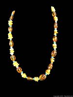 Full view of the amber and turquoise beaded necklace against a black background showing bead arrangement and length.