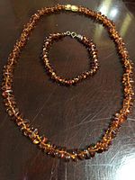 Photo showing the amber necklace and bracelet laid together on a dark surface to display the overall look and scale.