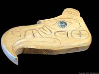 Front view of wooden First Nations Thunderbird carving showing engraved designs and abalone shell eye.