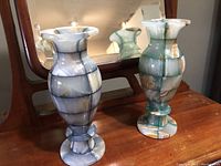 Pair of onyx mosaic vases, blue and green colors, placed on wooden surface in front of a mirror.