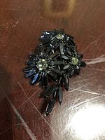 Front view of the Kramer brooch showing floral design in black marquise-cut and clear stones on wooden surface.