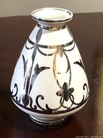 Front view of a white Beleek vase with black floral and scroll sterling silver overlay, showing the shape and condition of the rim and body.