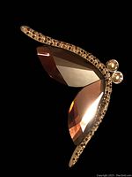 Close-up view of the Swarovski butterfly brooch showing the faceted pink crystal wings and rhinestone decorated gold-tone frame.