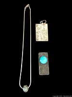 Full view showing all three items: necklace with turquoise bead, rectangular etched ring, and rectangular turquoise pendant.
