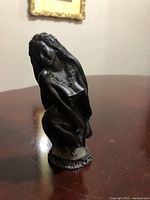 Front angle view of the carved lava Hawaiian dancer figurine on a wooden surface.