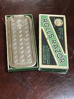 Metal razor case with embossed geometric design and Rolls Razor logo inside original box