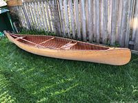 Side view of full length wooden canoe on grass