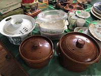 View of all casserole dishes on table including Turi Norway Market covered casserole, two brown ceramic covered casseroles, and additional glass and ironstone casseroles