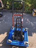 View of the blue plastic platform dolly with four swivel caster wheels and two black handheld metal dollies stacked inside.