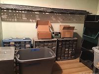 Photo of room corner with multi-drawer organizers, cardboard boxes, and plastic bins used for small hardware parts storage.