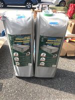 Two grey zipped carry bags containing foldable bed systems standing upright