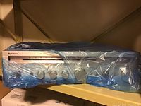 Hitachi SR-6010 AM-FM stereo receiver wrapped in protective blue plastic on a shelf