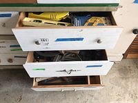 Full view of 3 partially open drawers showing various tools including a yellow tape measure, several spirit levels, corner clamps, hammers, axes, and more.