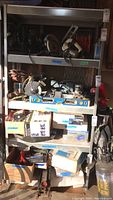 Full view of metal utility shelf with multiple shelves holding various power tools and boxes.