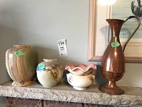 Full view of all four items: two marble vases, ceramic planter with pink ruffled edge, and tall copper jug with handle.