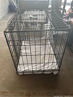 Black metal wire animal crate viewed from the top with white mattress on removable plastic floor tray inside.