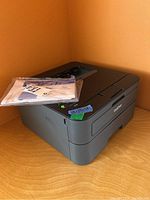 Brother laser printer with manuals visible on top, showing front and top view of device.