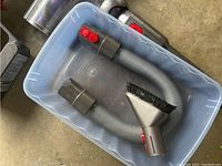 Close-up photo of flexible hose and brush attachments in plastic bin