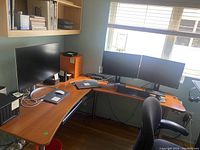 L shaped office desk in room with two monitors, chair, and office accessories showing the full desk setup.