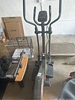 Elliptical machine visible from the front showing pedals and handlebars, located in a garage space.