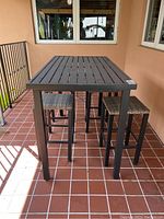 View of full patio table with four matching stools arranged around it on tiled floor.