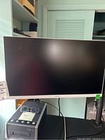 Full front view of the Samsung monitor on a stand, showing the screen and bezel, with some dust on the surface.