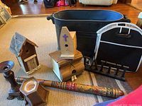 Photo of entire lot showing black metal tub, three wooden bird houses with distinct designs, wooden candle holder, custom painted carved baseball bat, and 'FAITH' sign.