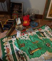 Overview image showing multiple harmonicas, pewter fish figurine, Yeti mugs, shamrock picture frame, wine history book, Cape Cod themed cards, and Irish-themed cloth/map laid on floor.
