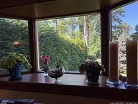 Photo of window ledge with four succulent plants in various decorative pots and three used pillar candles in earth tones.