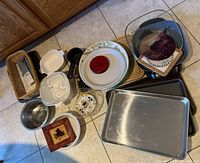 Overview of various kitchen items including cookie pans, casserole dishes, measuring cup, cutting board, basket of utensils and decorative dishes.