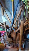 Photo showing various shovels, pick axe, and sledgehammer with mostly wooden handles, exhibiting oxidation and wear.