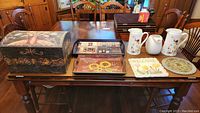 Photo of the entire lot including the memory chest, two trays, three pitchers, and two stepping stones on a wooden table.