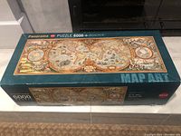 Box of 6000 piece panorama puzzle with vintage world map art, showing front and top sides.