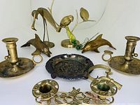 Wide view showing all brass pieces including candle holders, dolphins, birds on a branch, and ashtray.