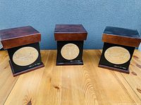 Three Clarence Wells indigenous-themed decorative boxes with wooden lids and metal embossed plaques shown facing forward.