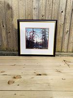 Front view of framed print against wooden fence showing the entire artwork and frame.