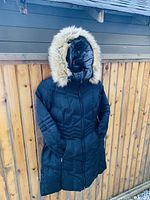 Front full-length view of black women's parka with hood trimmed in faux fur, showing overall condition and design.