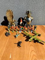 Full view of all items in the lot showing figurines, airplane, bust, and eagle on wooden surface with grey background.
